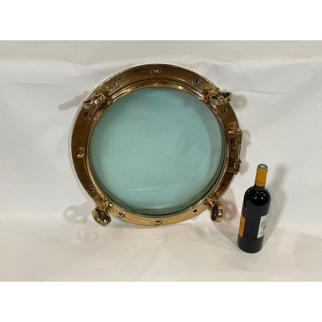 Early 20th century solid brass ships porthole. Hinged door with four dog bolts. Clear glass. Highly polished and...