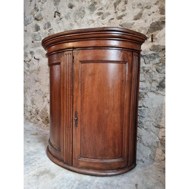 Antique demi-lune cabinet crafted from solid walnut wood, dating from the late 18th century and originating from a French...