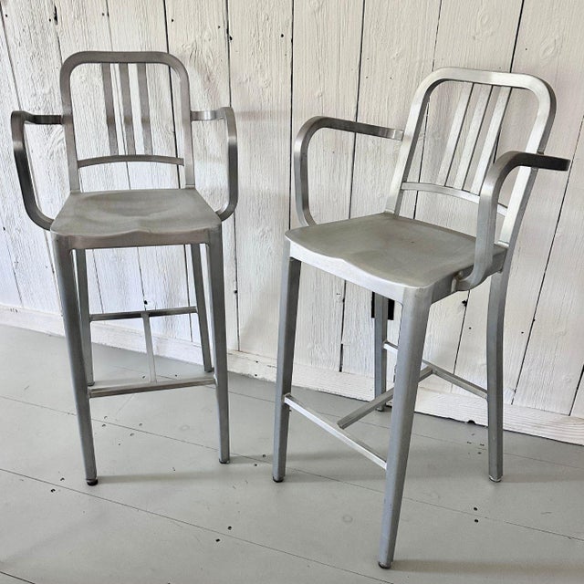 A clean, architectural set of 2 Emeco brushed aluminum stools with arms, combining the brand’s unmistakable industrial...
