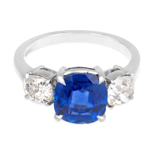 This exceptional Mid Century three stone ring centers on a richly saturated cushion cut blue sapphire weighing...