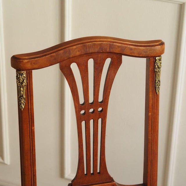 A stylish antique chair from the late 19th to early 20th century featuring an open-work backrest, a wicker seat, and...