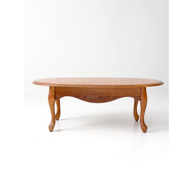 This vintage oak coffee table features a broad oval top, shaped apron, and graceful cabriole legs. Beautiful oak grain...