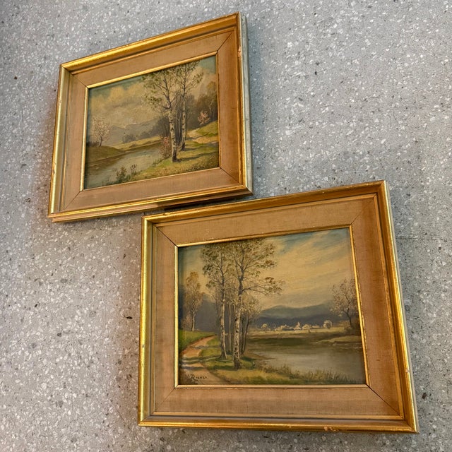 This charming pair of landscape paintings circa the 1960s captures a serene countryside setting, featuring winding paths,...