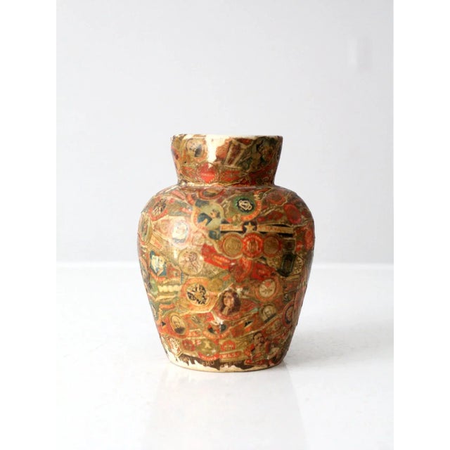 This is a vintage cigar band vase. Adorned with a collage of cigar paper ring bands, the ceramic vase displays a colorful...