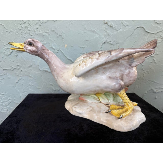 This vintage Italian porcelain figurine depicts a duck in a lively, expressive pose with wings partially outstretched,...