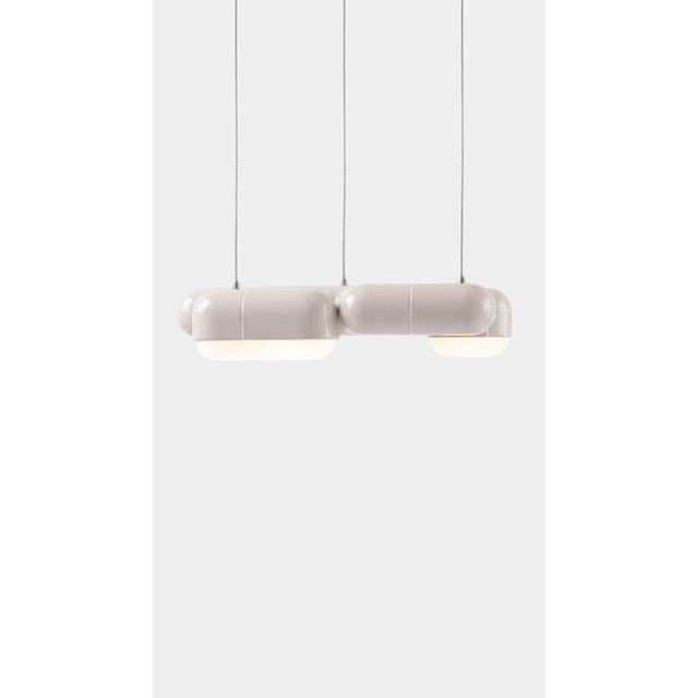A linear pendant made for the table everyone gathers around. The curved-tile module repeats along its length, so light...