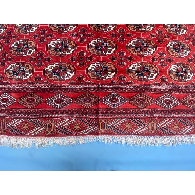 This Turkmen Tekke rug showcases a striking, repetitive pattern of guls arranged in rows, creating a visually captivating,...