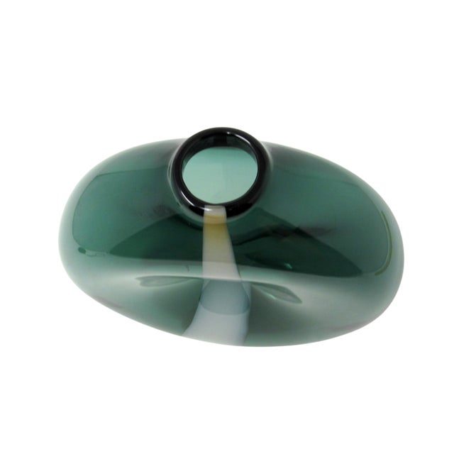 A hand-blown green and white and dimpled glass vase. This vase has a circular shape and narrow like a pocket vase. There...