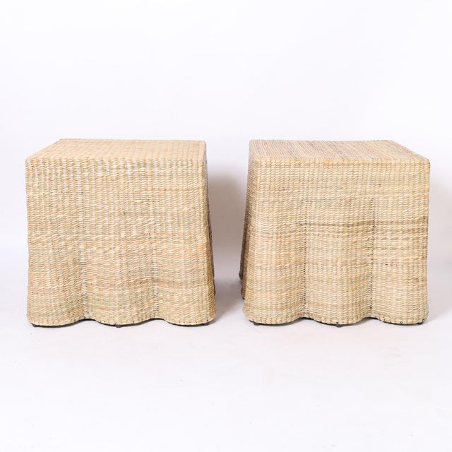 An in vogue pair of mid century inspired square ghost drapery tables hand crafted with a durable metal frame wrapped in reed.