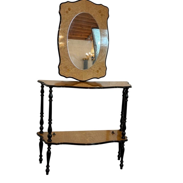 A striking Italian-style console table and matching mirror set with sculptural lines, rich black accents, and warm gold-...