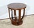 This circular pedestal table features a four-leaf rosewood veneer top. The top rests on four legs with recesses on the...