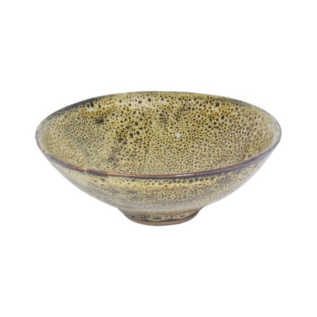 A studio pottery bowl by the American artist Abraham Cohn (born 1925). This round bowl has a beige-yellow glaze with dark...