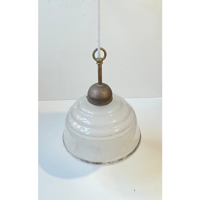 Art Deco or Bauhaus era styled hanging lamp featuring a frosted glass shade with black stripe and a patinated top in...