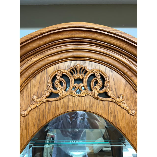 Design Plus Gallery presents a Vintage Oak Curio Cabinet from Pulaski Furniture. The classic arched cabinet is elegantly...