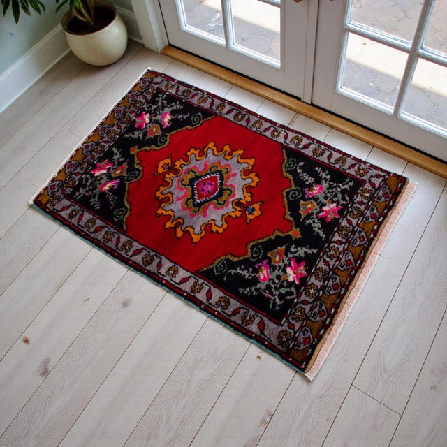 This vibrant vintage Turkish Oushak rug showcases a striking crimson field grounded by deep charcoal corners and a...