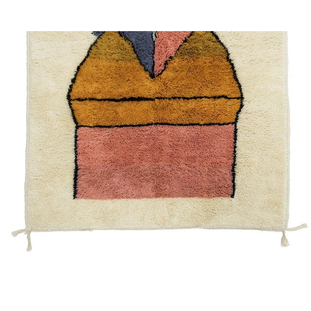 Stunning hand-knotted wool rug showcasing an abstract face motif in muted tones of Misty Jade, Coral Pink, Buff Orange,...
