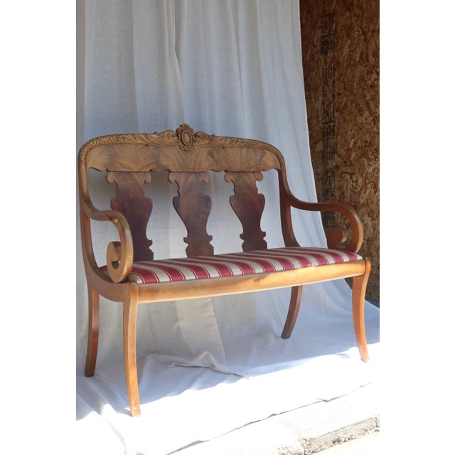 A beautifully carved antique walnut settee in the Empire / Biedermeier tradition, featuring the graceful proportions and...
