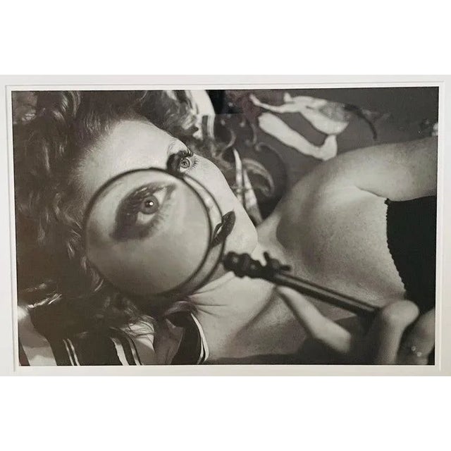 A photography archival pigment print of a a woman holding a reading magnifier close to her eye in black and white by...