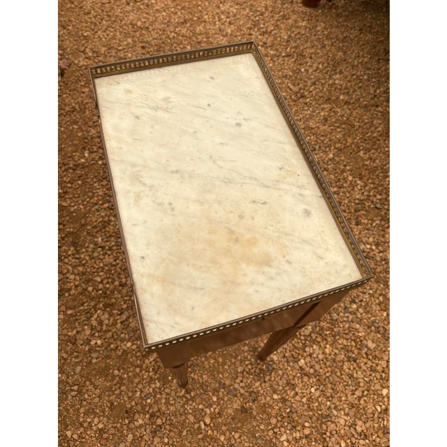 French Louis XVI style mahogany bedside table, 20th c., having inset marble top with pierced gilt-metal three-quarter...