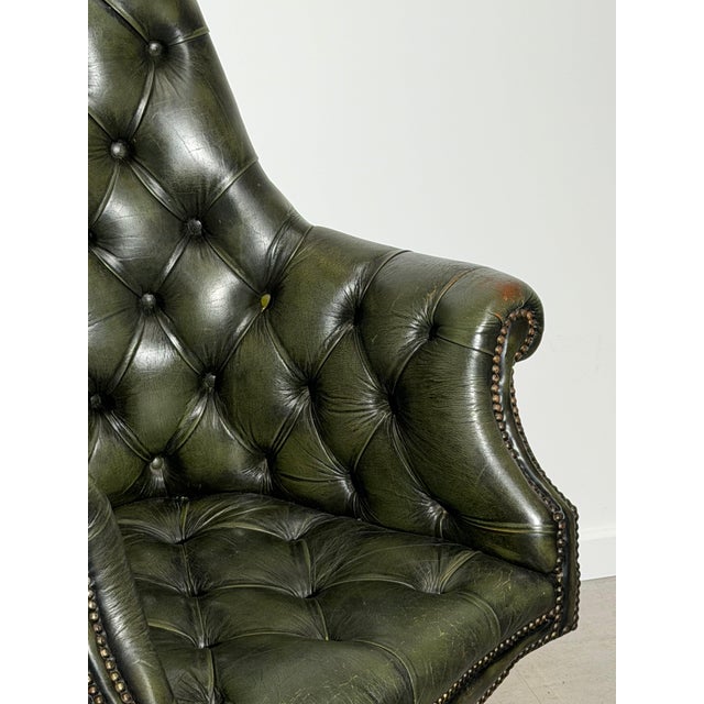 Elegant vintage swivel director’s chair in the classic Chesterfield style, upholstered in deep green button-tufted leather...