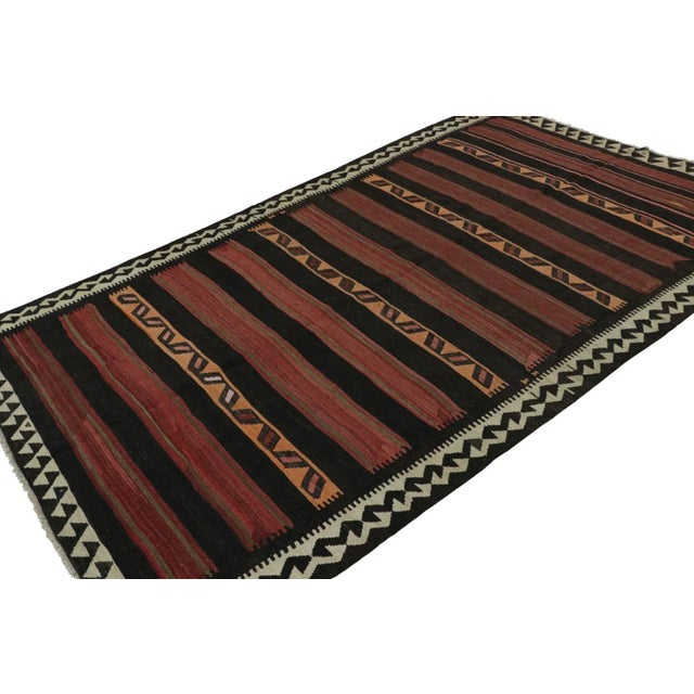 Handwoven in wool, circa 1950-1960, this 6x10 vintage Afghan tribal kilim, in masculine hues of brown, red, orange, black...