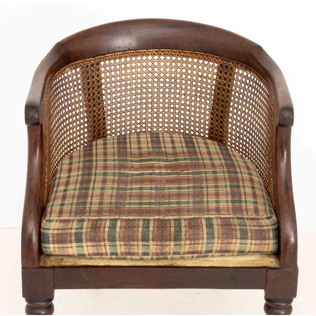 Regency Cane Paneled Mahogany Bergere, 19th century, with rush seat and plaid upholstered cushion four turned wood legs...