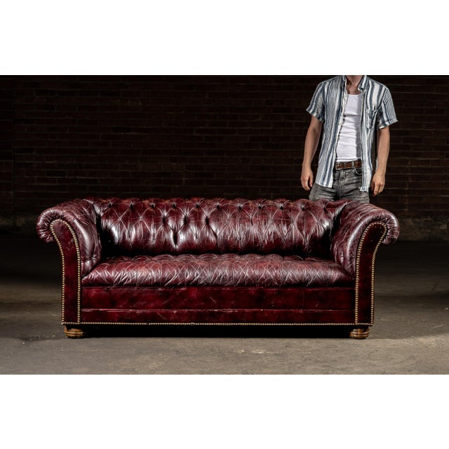 Mid-20th Century; Origin Unmarked (English Style) Classic three-seat Chesterfield sofa upholstered in deeply patinated...