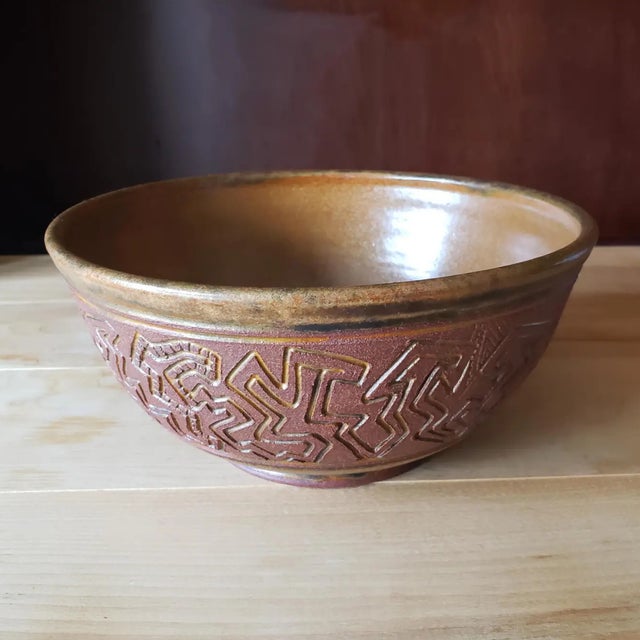 A striking California studio pottery bowl in deep red stoneware with a carved geometric relief, finished with a satin-...