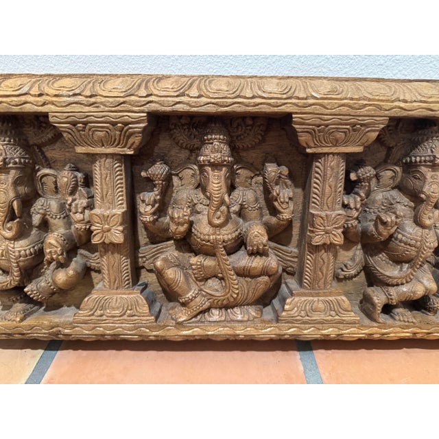 This striking vintage South Indian hand-carved wooden architectural panel features multiple seated depictions of Ganesha,...