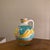 A beautifully handcrafted vintage pottery pitcher featuring warm sun-washed tones and an organic bohemian silhouette. This...