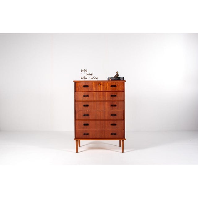 Elegant mid-century modern chest of drawers in warm teak veneer, dating from the 1960s. The piece features a clean...