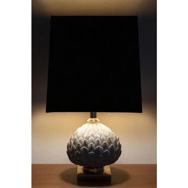 A chic table lamp with brass and porcelain. It has a beautiful shade with a detailed base that has porcelain leaves. In a...