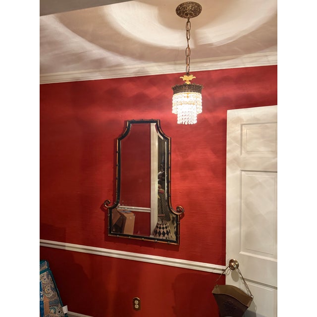 An elegant Uttermost wall mirror featuring a distinctive faux bamboo frame accented by graceful scrolled lower corners....