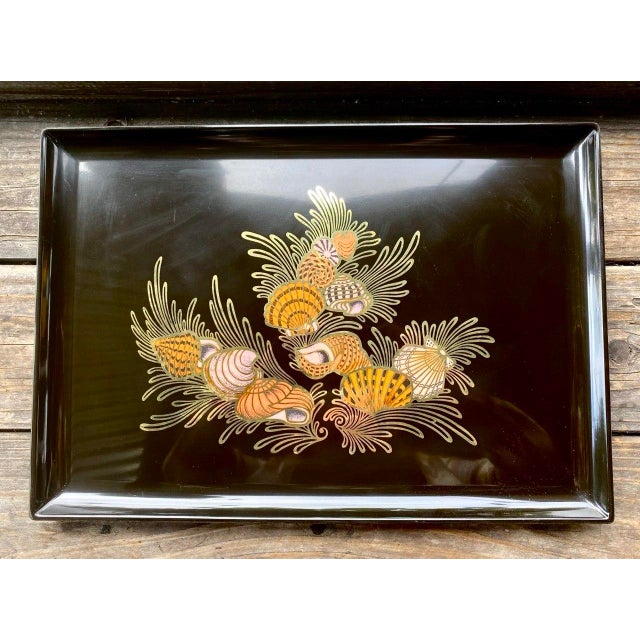 A striking vintage Couroc of Monterey serving tray featuring an exuberant arrangement of colorful seashells nestled among...