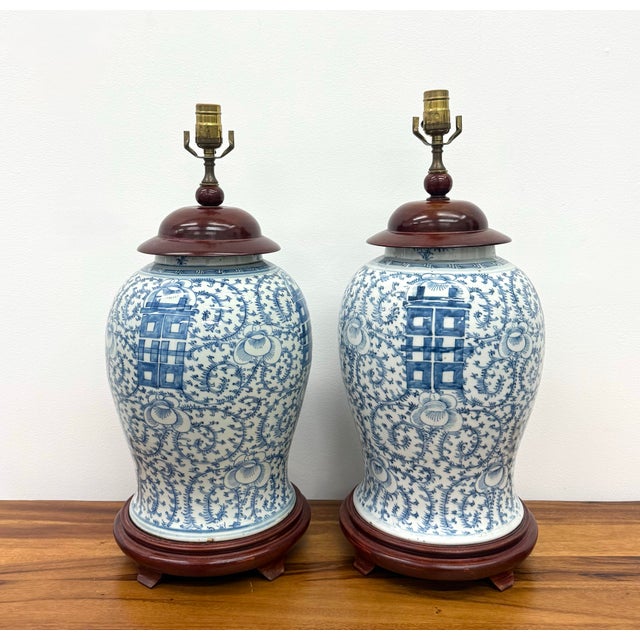 A classic pair of blue and white porcelain ginger jar table lamps featuring an intricate floral vine motif accented by...