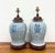 A classic pair of blue and white porcelain ginger jar table lamps featuring an intricate floral vine motif accented by...