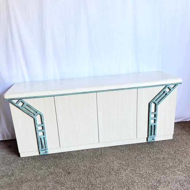 A sculptural statement rooted in coastal charm, this postmodern credenza features a pale wood grain laminate body...