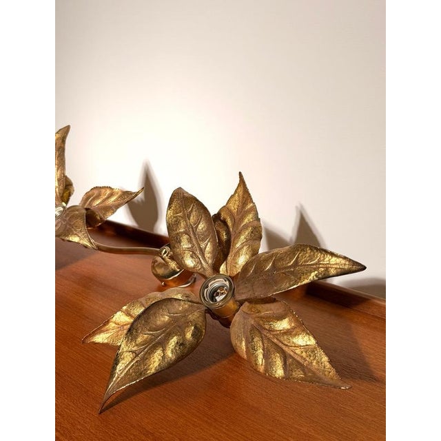 Elegant vintage wall lamp featuring two sculptural leaf-shaped light points connected by a flowing curved arm. Crafted in...