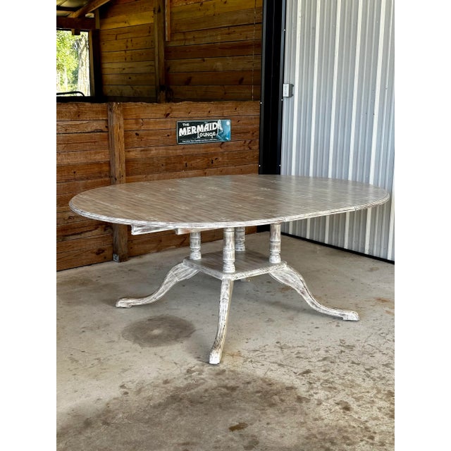 A substantial custom dining table by Modern History Home featuring a beautifully aged, distressed painted finish and...