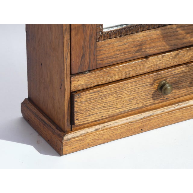 Small antique wooden cabinet with a mirror in the front door. The apothecary has beautiful carved details around the...