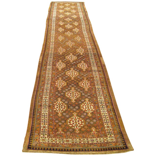 An antique Persian Hamadan Camel Hair oriental rug, in long runner size, with a repeat design in the central field. Circa...