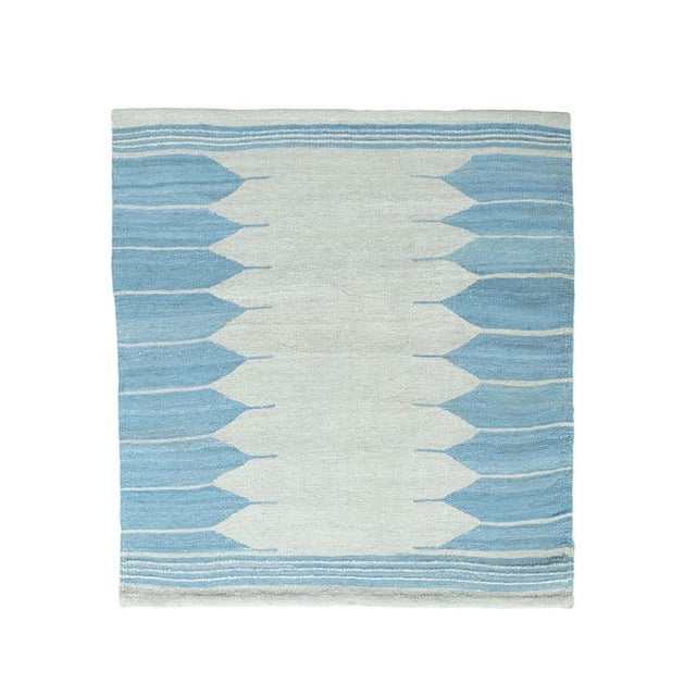 This handwoven Mazandaran kilim impresses with a modern, minimalist design and a harmonious color palette in light blue...