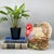 Colorful ceramic turkey cookie jar with a bright red head, layered feathers, and berries tucked among the leaves at its...