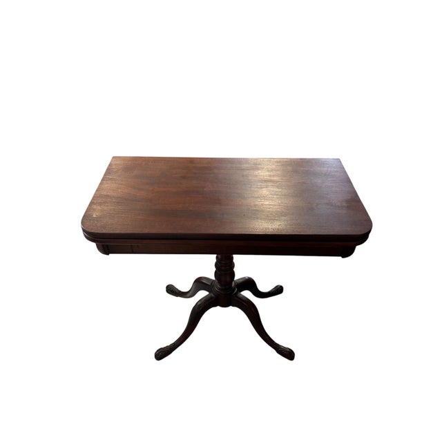 A handsome traditional card table in a rich mahogany tone, featuring a rectangular top with softly rounded corners, a...