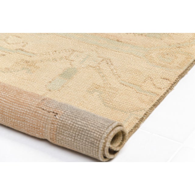 This is a vintage Turkish Oushak rug from the Mid 20th Century. The piece was hand-knotted.