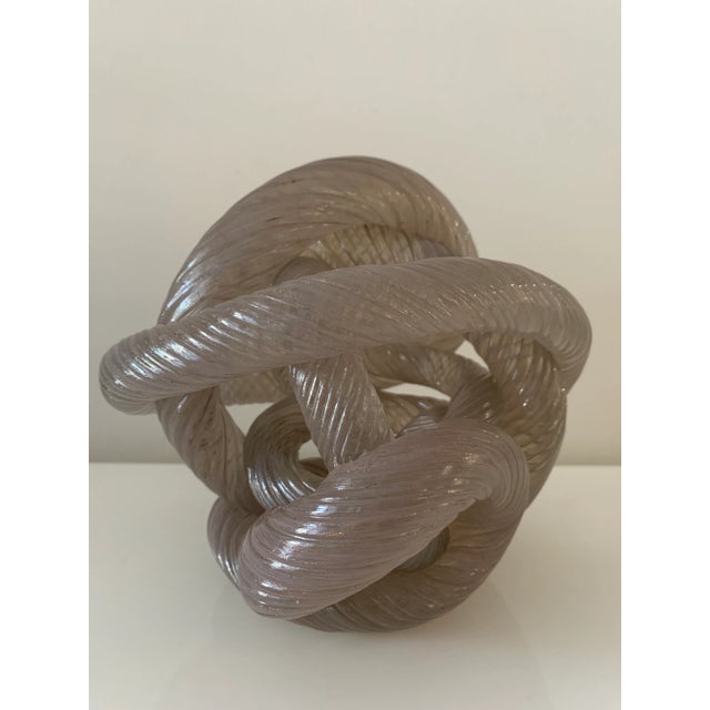 Vintage, thick sculpture depicting an intertwining knotted rope in shimmering, iridescent pinkish glass. Contorted and...