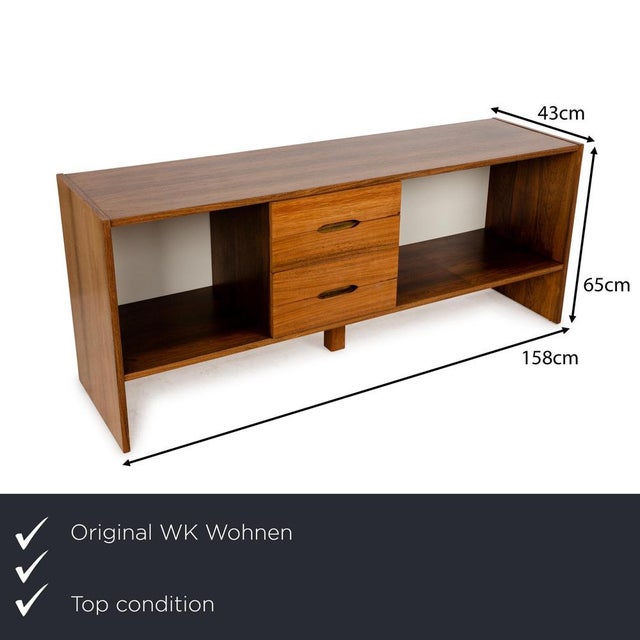 The sideboard from WOK Wohnen is made of brown wood and stands on floor-level side panels. It is characterized by its...