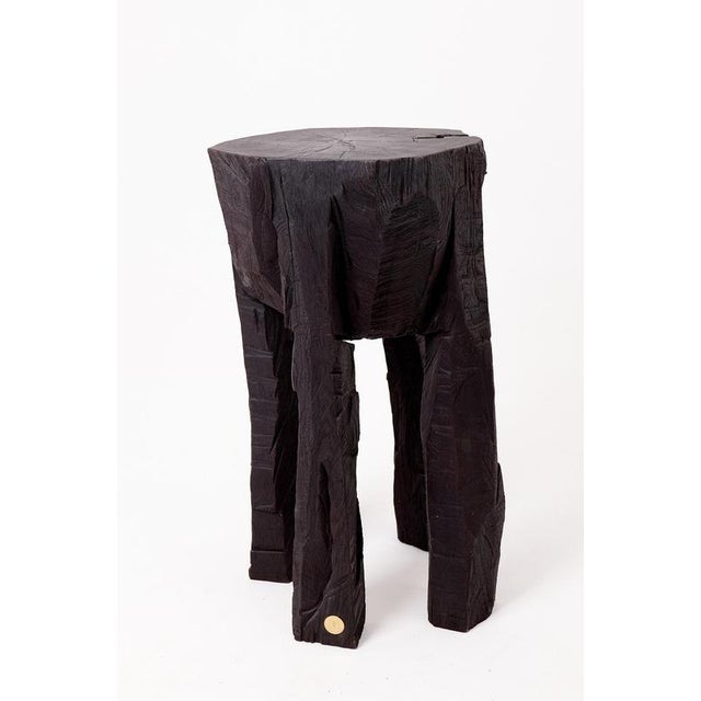 Hand-carved from a single solid hardwood log, this tall side table possesses a striking architectural presence and a...