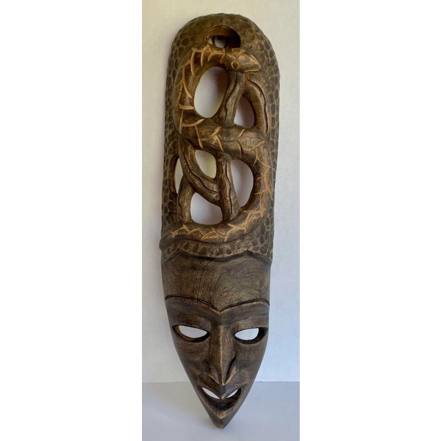 Here is a fantastic hand-carved tribal mask made to hang on a wall. The piece features a mask/face on the bottom with an...