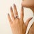 An elegant Art Deco–inspired ring featuring a deep red, square-cut garnet at its center, framed by a geometric pattern of...